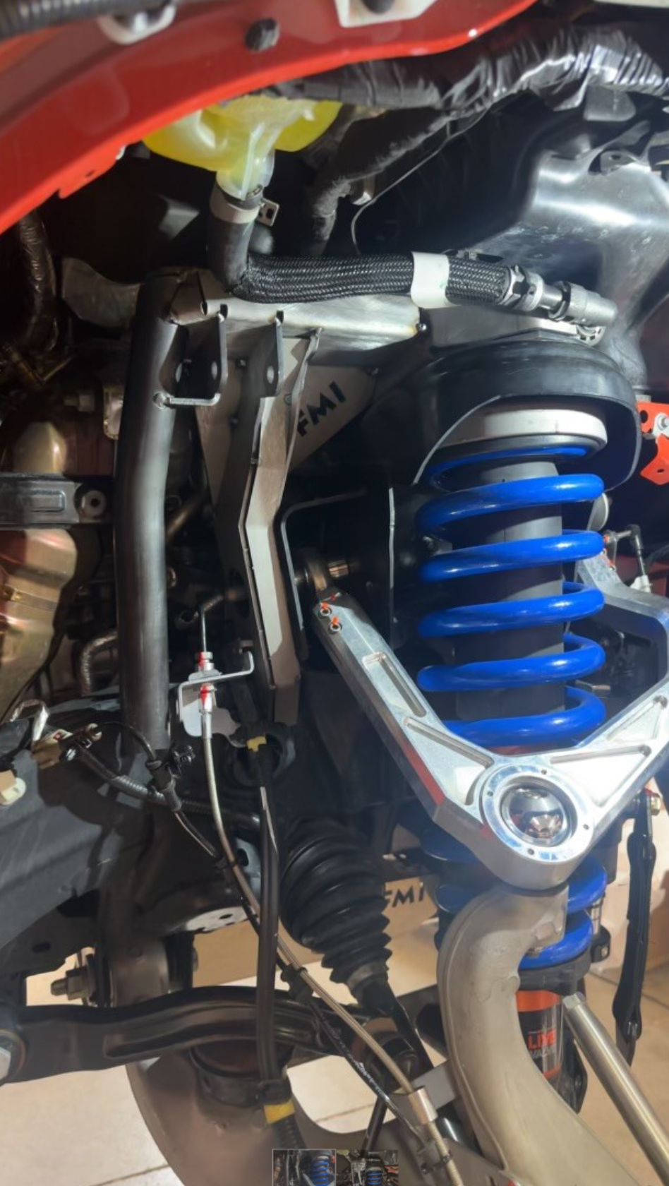 2022 Bronco Raptor fabricated front bypass shock mount kit showcasing blue shock and metal components for enhanced offroad performance.