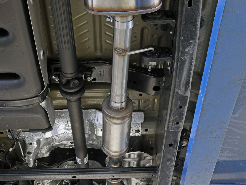 aFe Vulcan Series resonator upgrade pipe installed on a vehicle's exhaust system, showcasing its stainless steel construction and design.