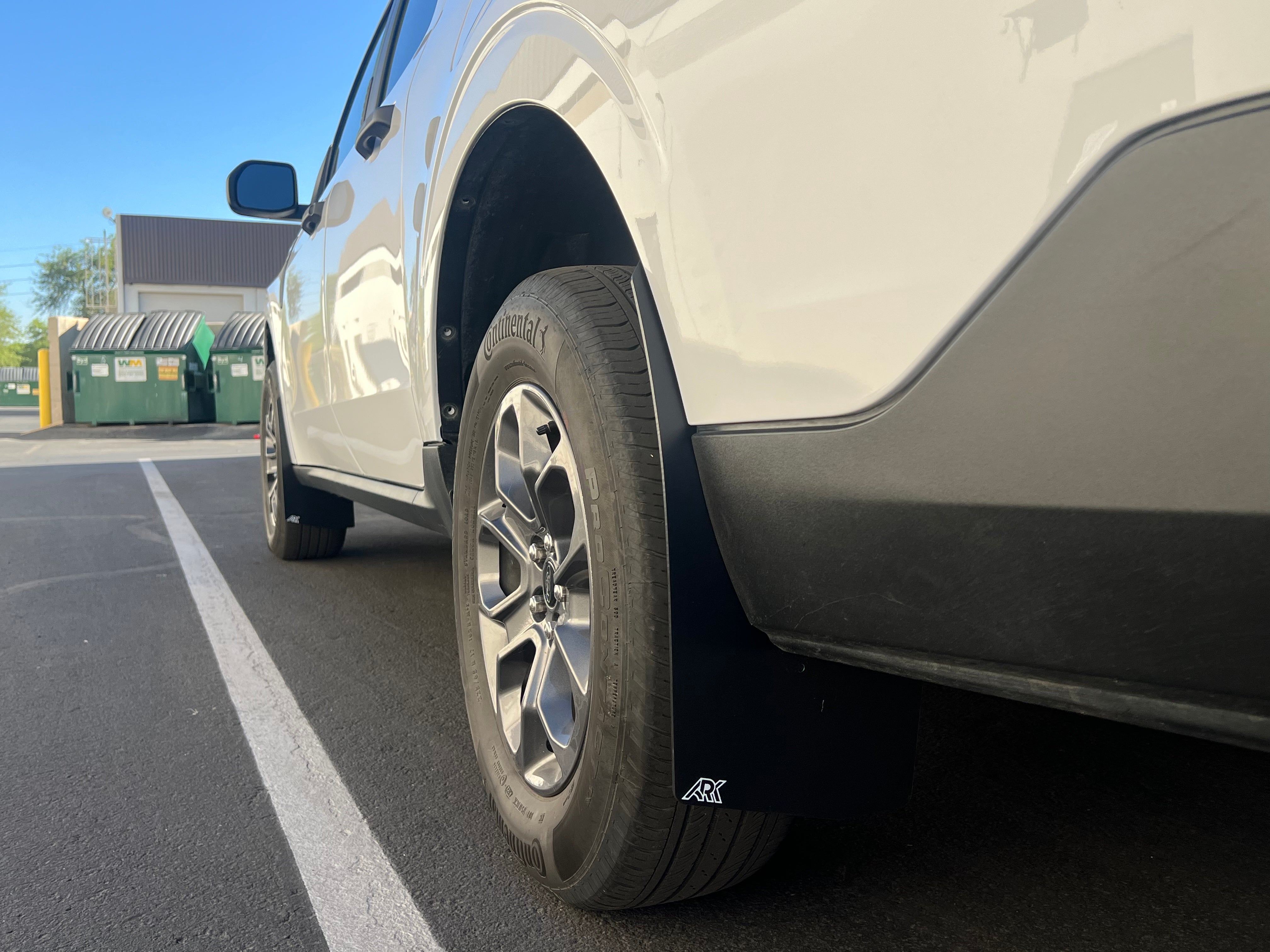 2022+ Ford Maverick with mud flaps installed, showcasing tire and wheel details in a parking lot setting.