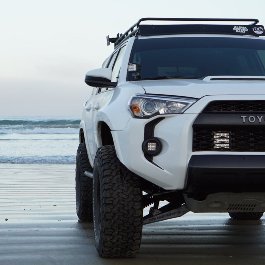 Toyota 4-Runner with upgraded fenders parked on the beach, showcasing offroad capabilities and rugged design.