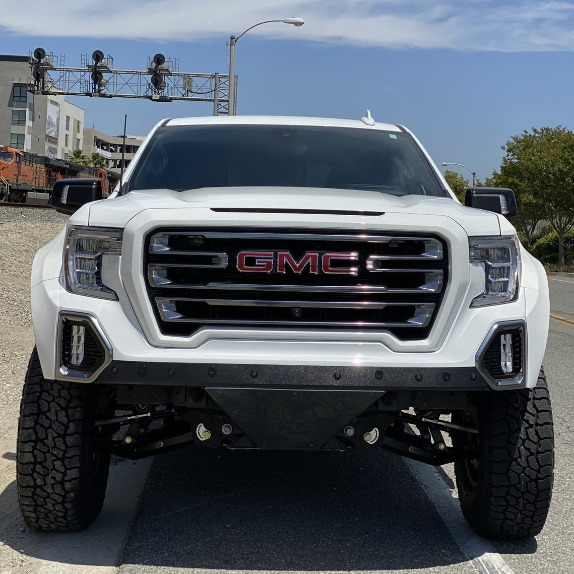 2019-2025 GMC Sierra fenders showcased on a lifted white truck with a bold front grille and rugged tires.