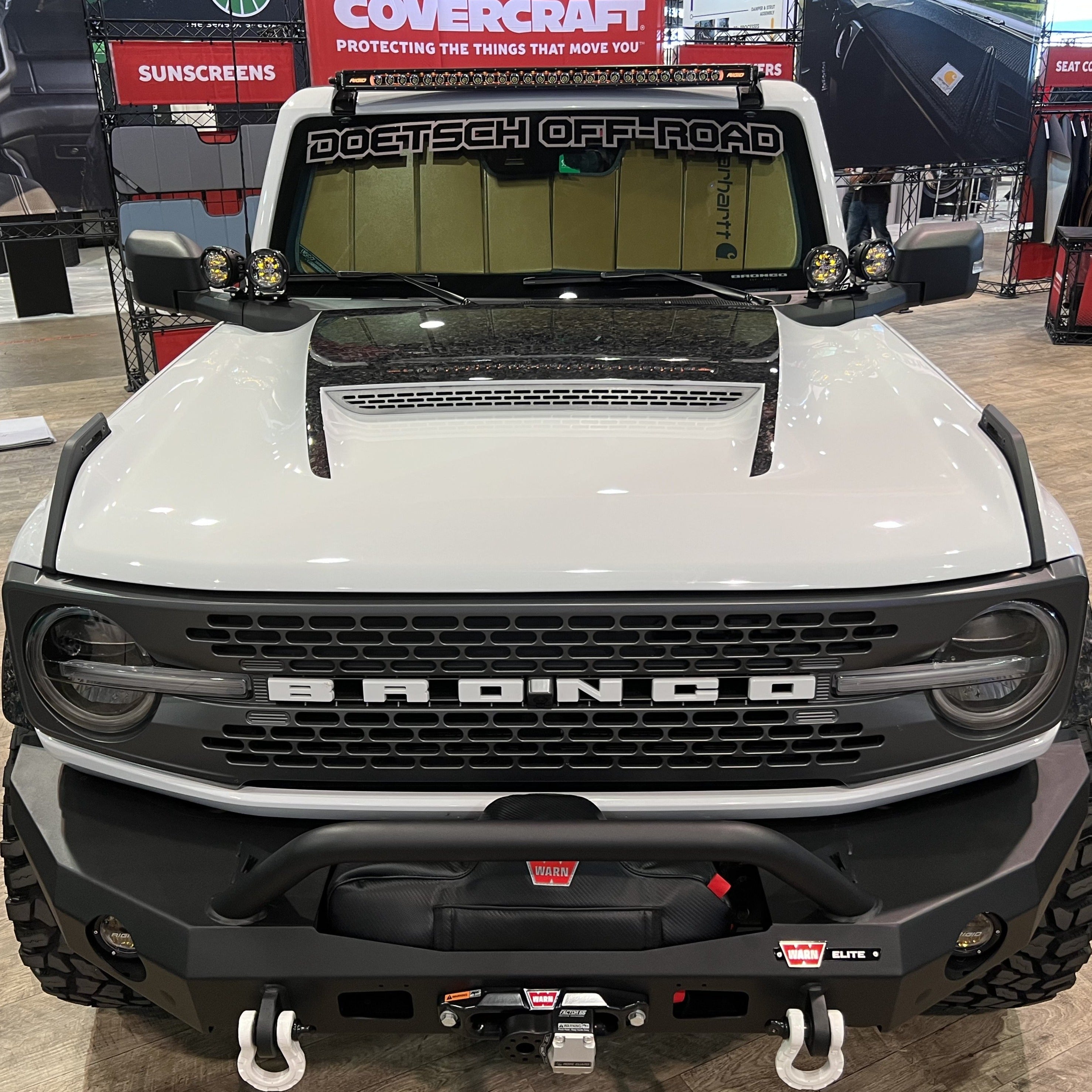 2021-2025 Ford Bronco with a Ram Air Hood showcasing a rugged design and offroad accessories in a showroom setting.