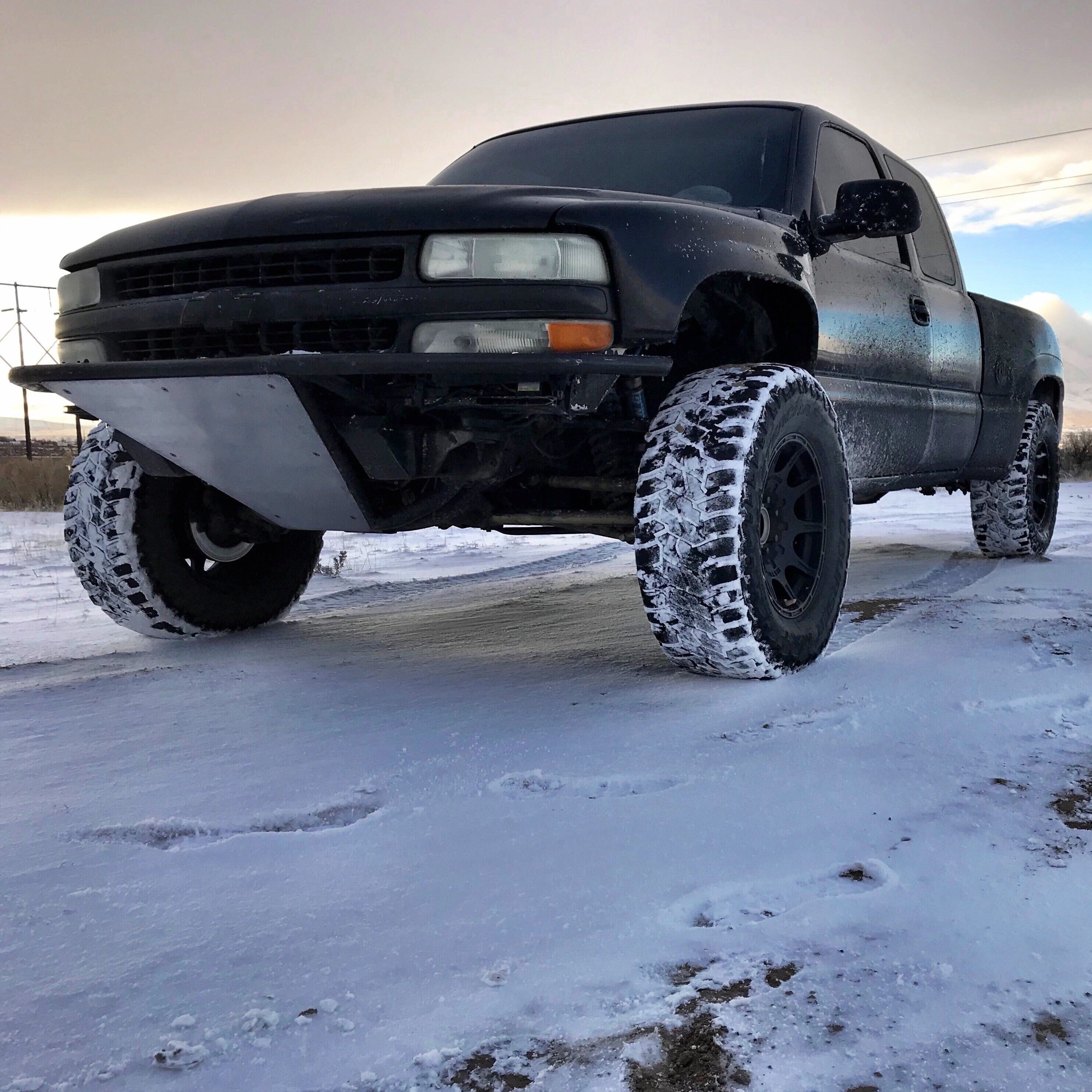 1999-2002 Chevrolet Silverado fenders on a lifted black truck in snowy terrain, showcasing offroad capability and style.