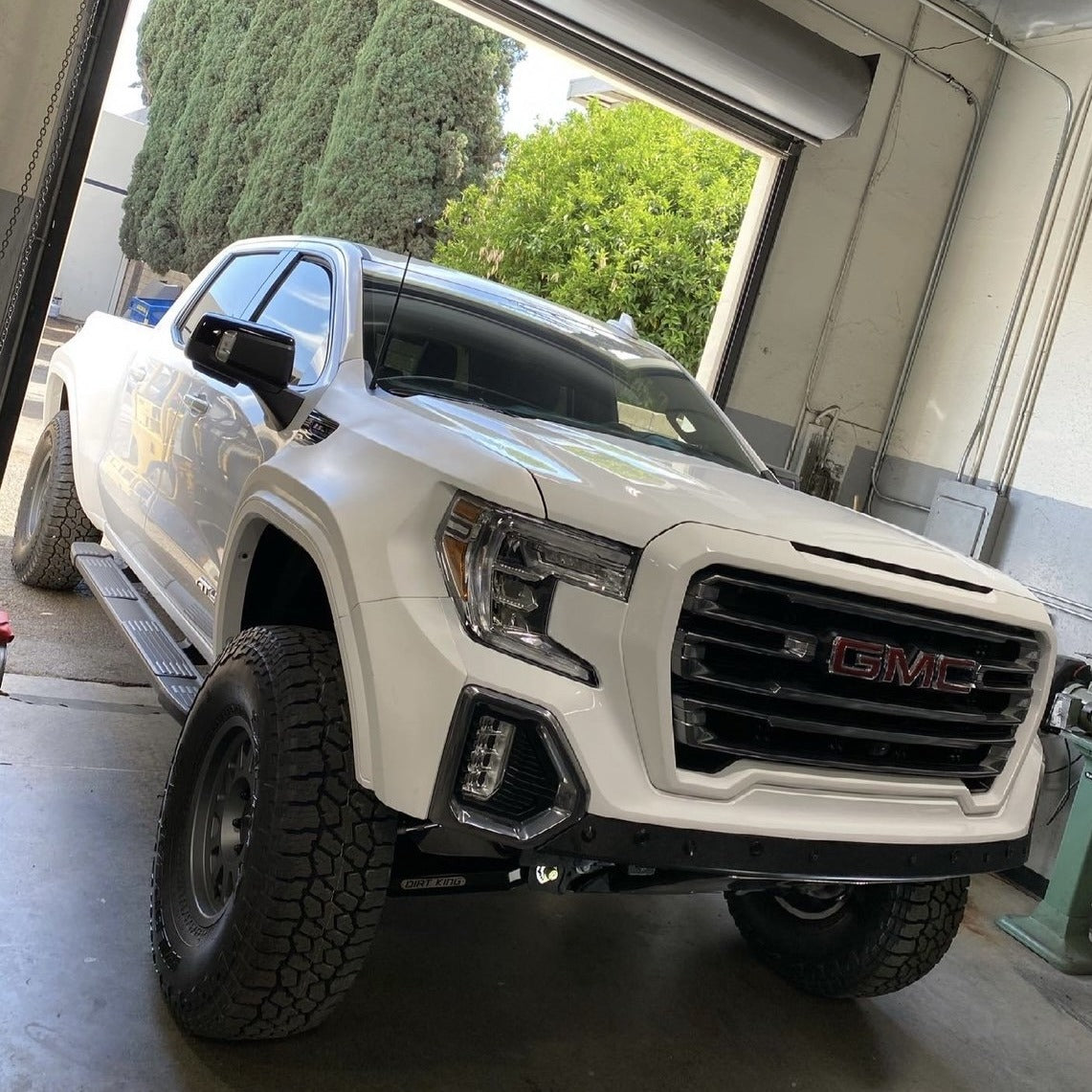 2019-2025 GMC Sierra fenders displayed on a modified white truck in a garage setting, showcasing offroad capabilities.