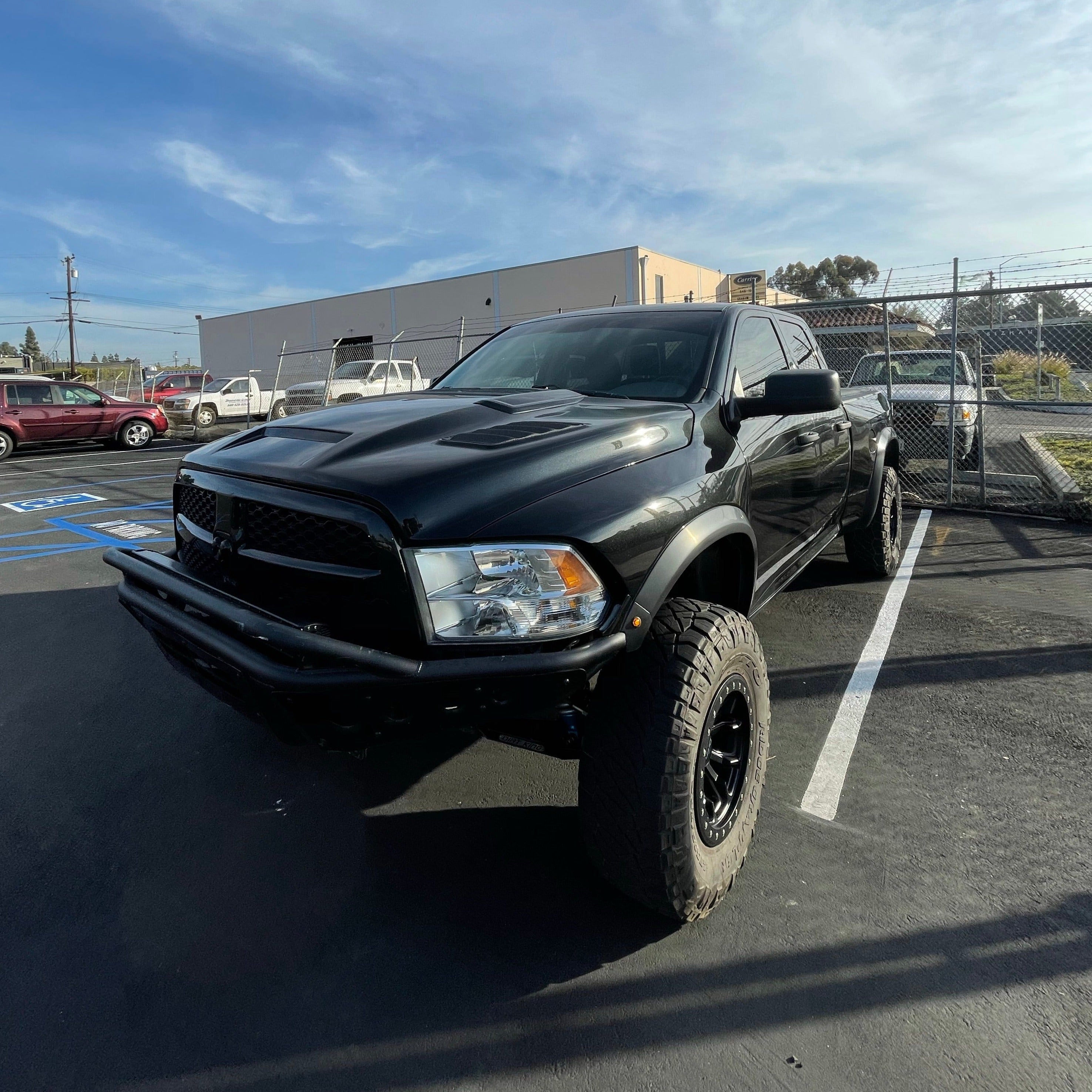 2009-2018 Dodge Ram TRX Kit installed on a black truck with off-road tires, parked in a lot.