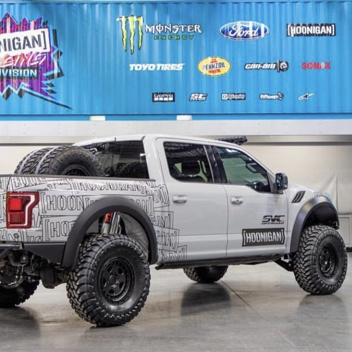 2017-2020 Ford Raptor with custom fenders, showcasing offroad capabilities and rugged design in a showroom setting.