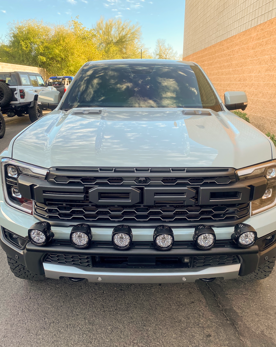 2024 Ranger Raptor Front Light Mount Kit installed on a stock bumper, featuring multiple auxiliary lights for enhanced visibility.