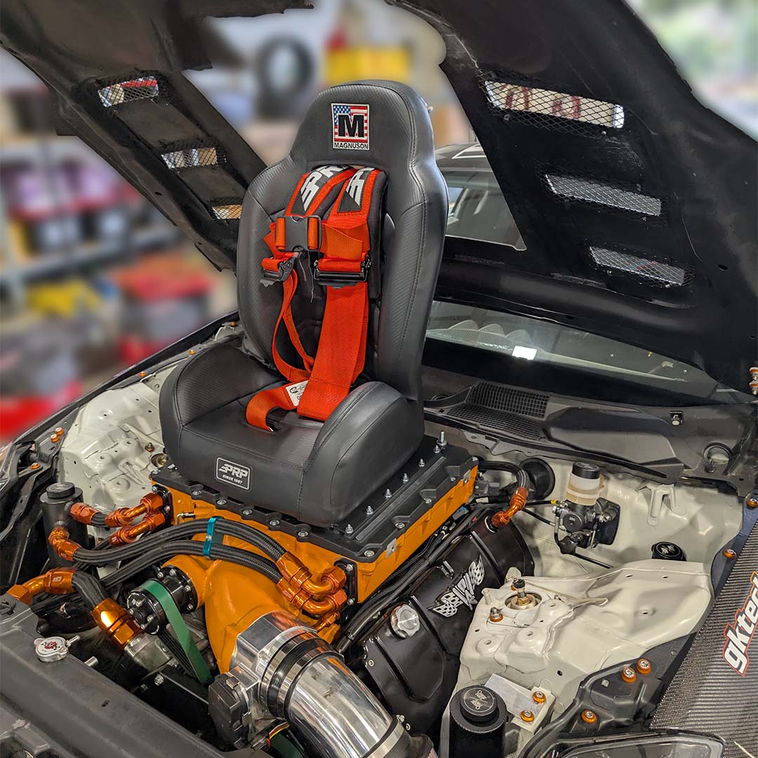 High-performance B.O.O.S.T.E.R. S.E.A.T. installed in a modified engine bay, showcasing its racing design and secure harness.
