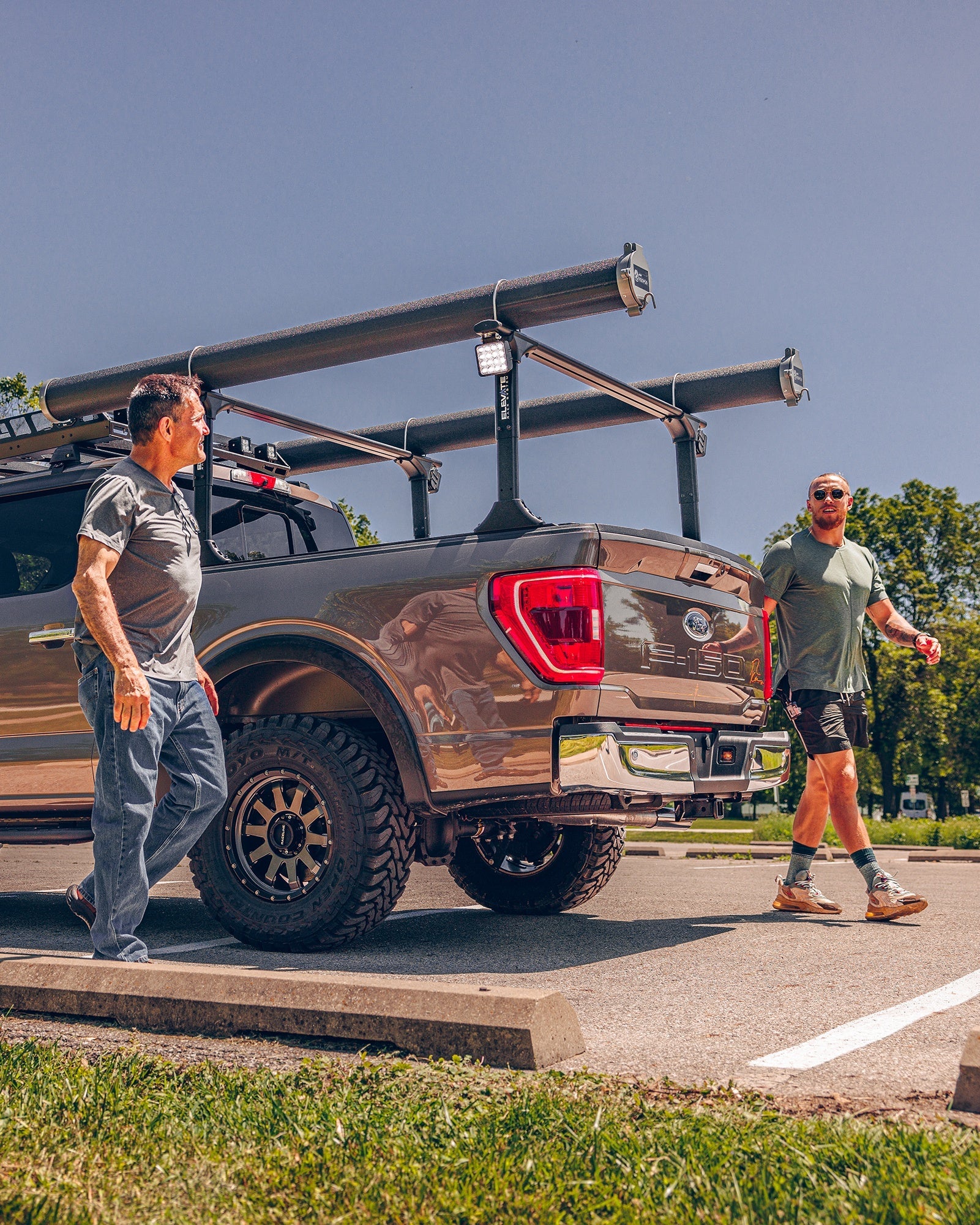 Men walking by a truck equipped with offroad gear, showcasing the rugged design and functionality of the vehicle.