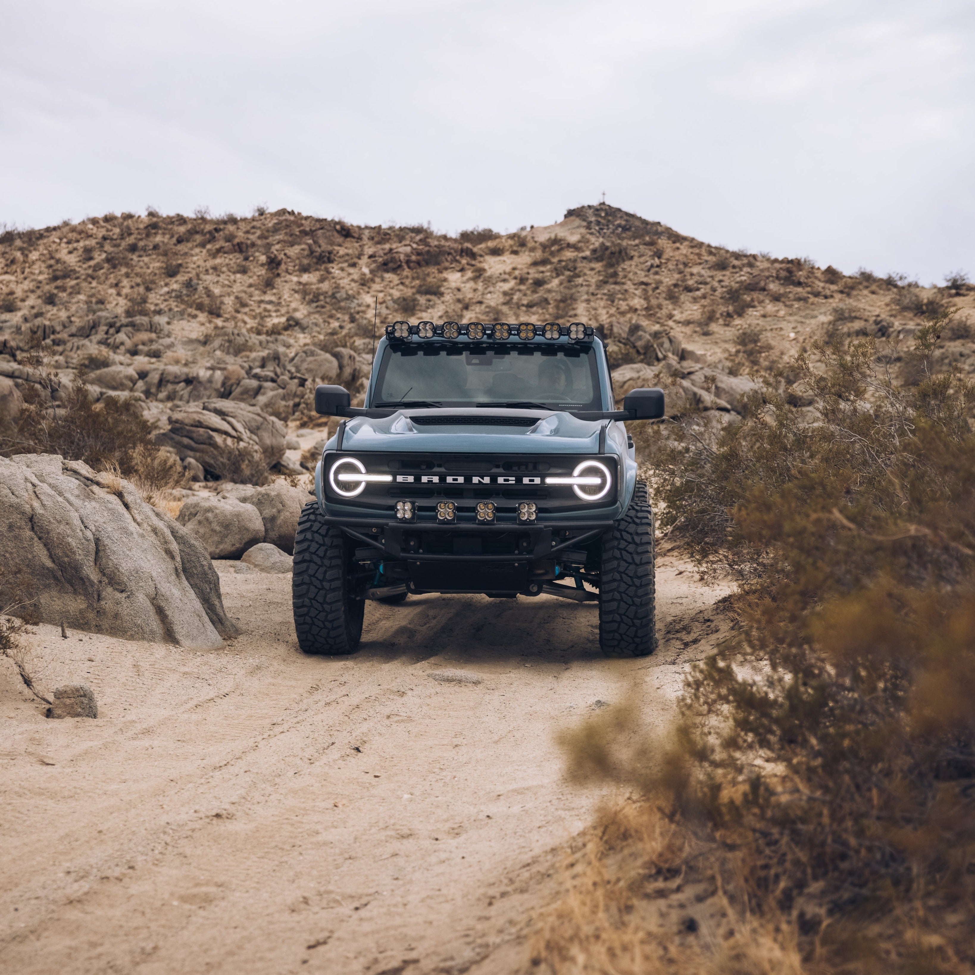 2021-2024 Ford Bronco with a Ram Air Hood, showcasing rugged design on a desert trail with rocky terrain.