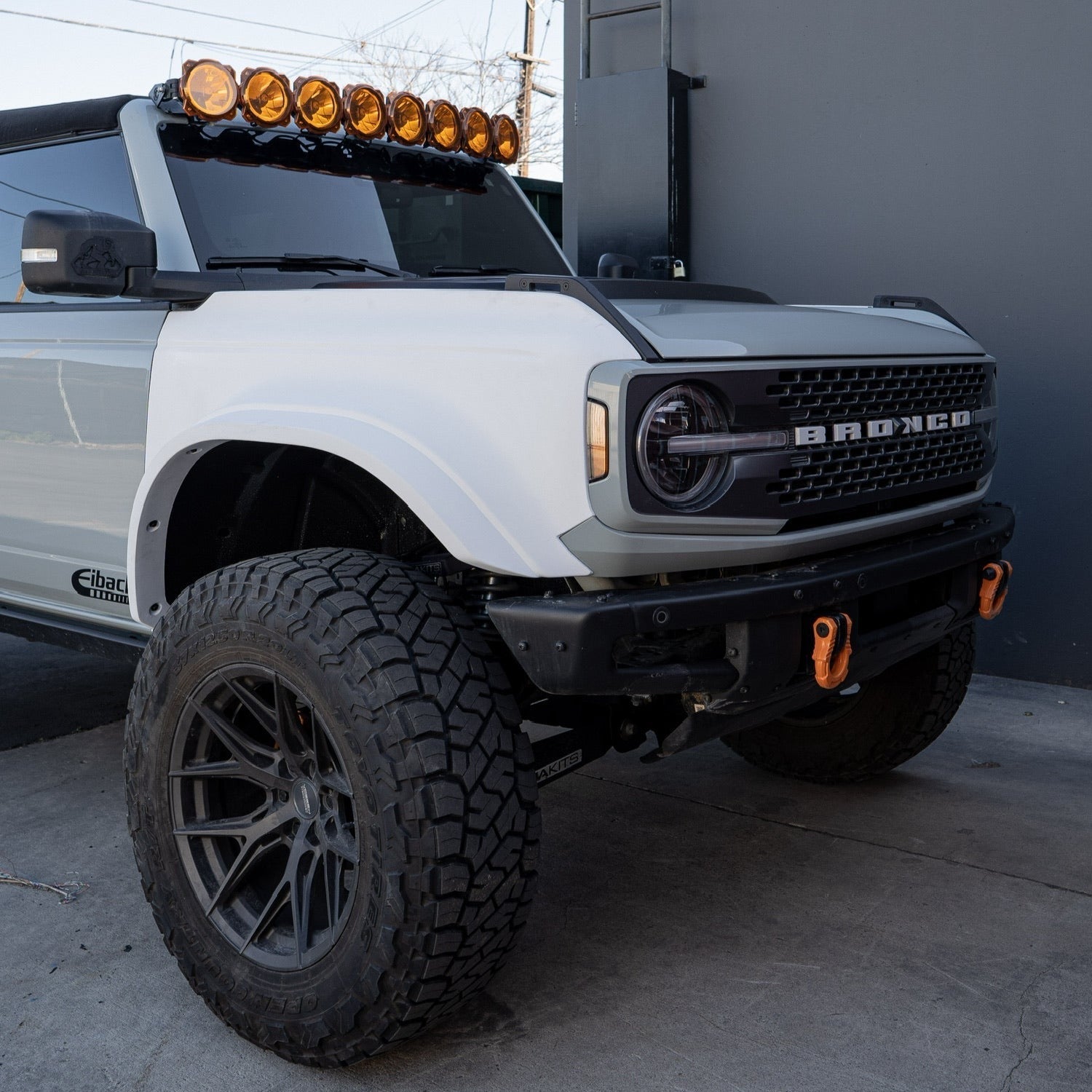 2021-2024 Ford Bronco with aftermarket fenders, off-road tires, and roof-mounted lights, showcasing rugged design.