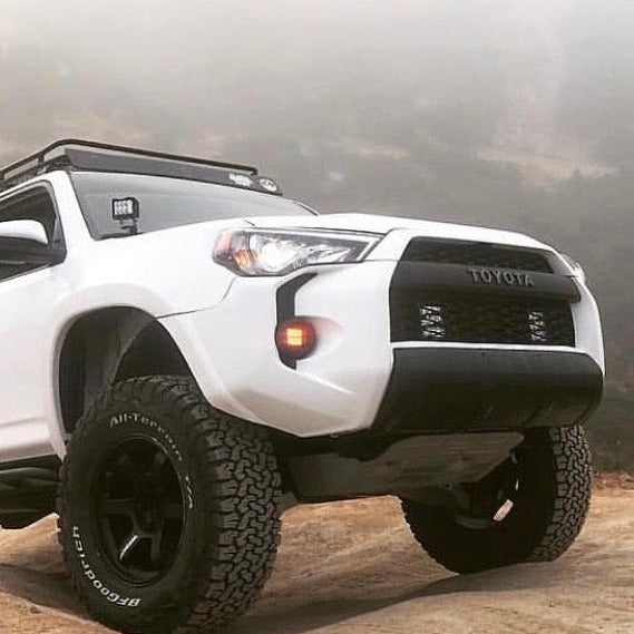 Toyota 4-Runner with upgraded fenders, showcasing an offroad-ready design and rugged tires in a foggy landscape.