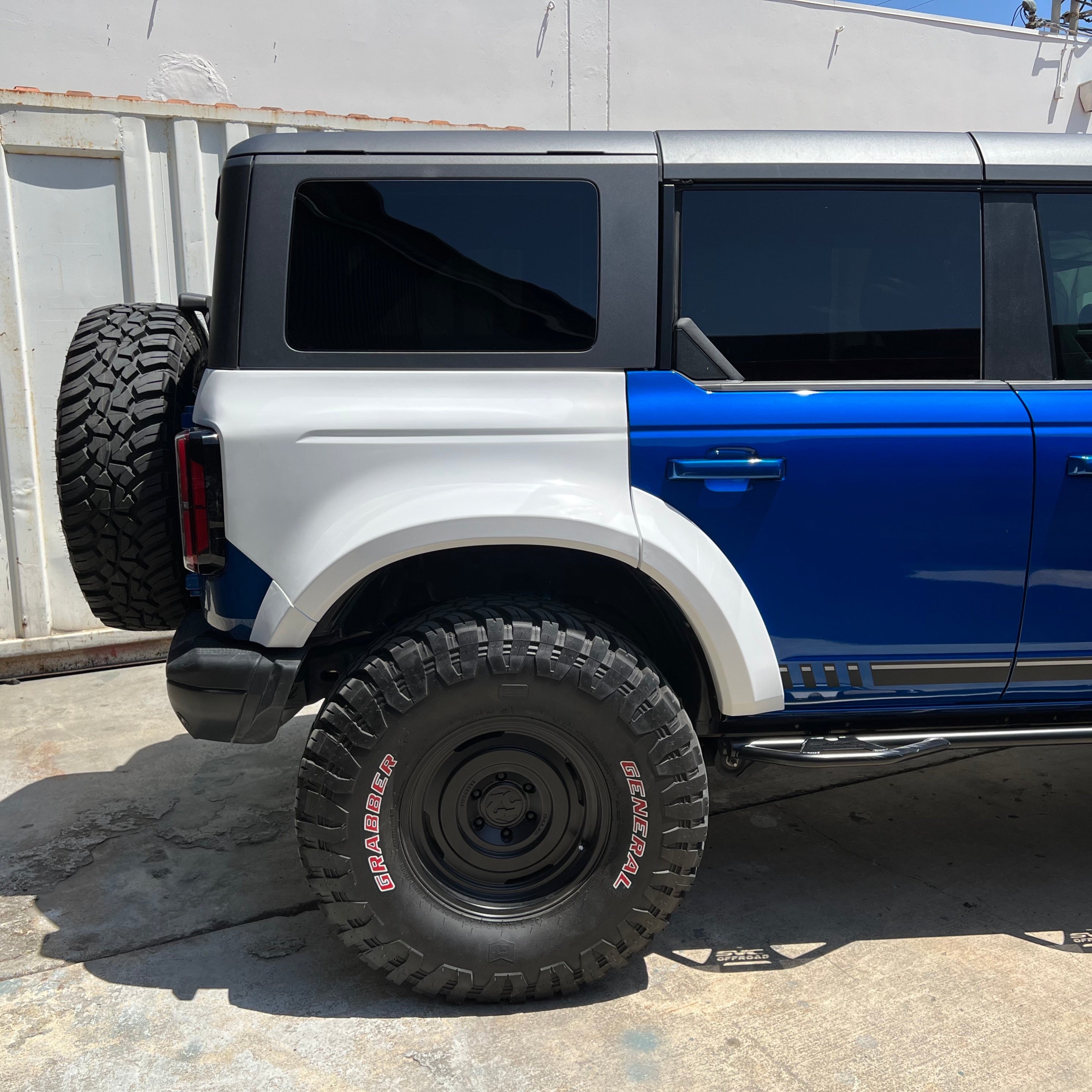 2021-2022 Ford Bronco 4-Door Rear Quarter Kit installed on a blue and white vehicle, showcasing rugged offroad tires.