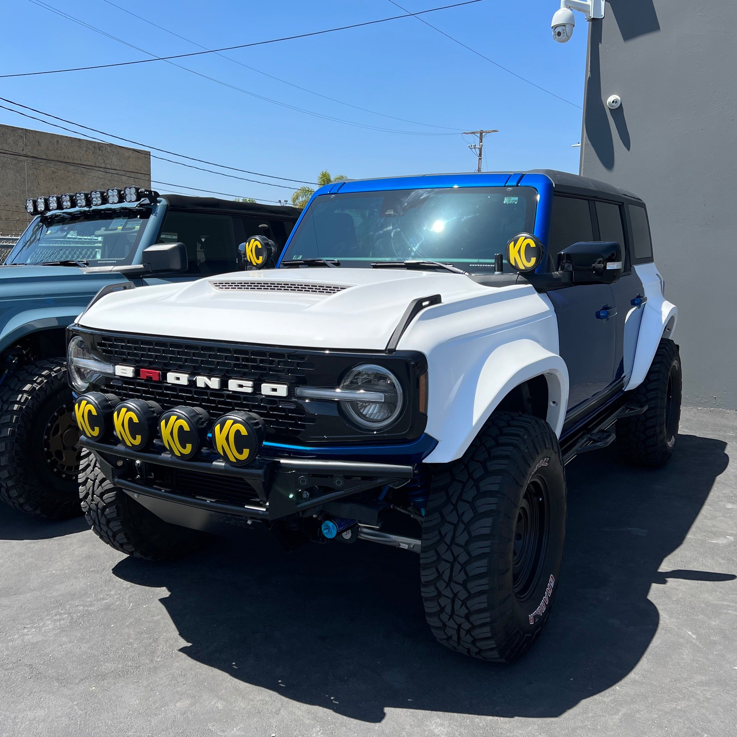 2021-2022 Ford Bronco with custom fenders, showcasing an offroad-ready design and rugged tires in a showroom setting.