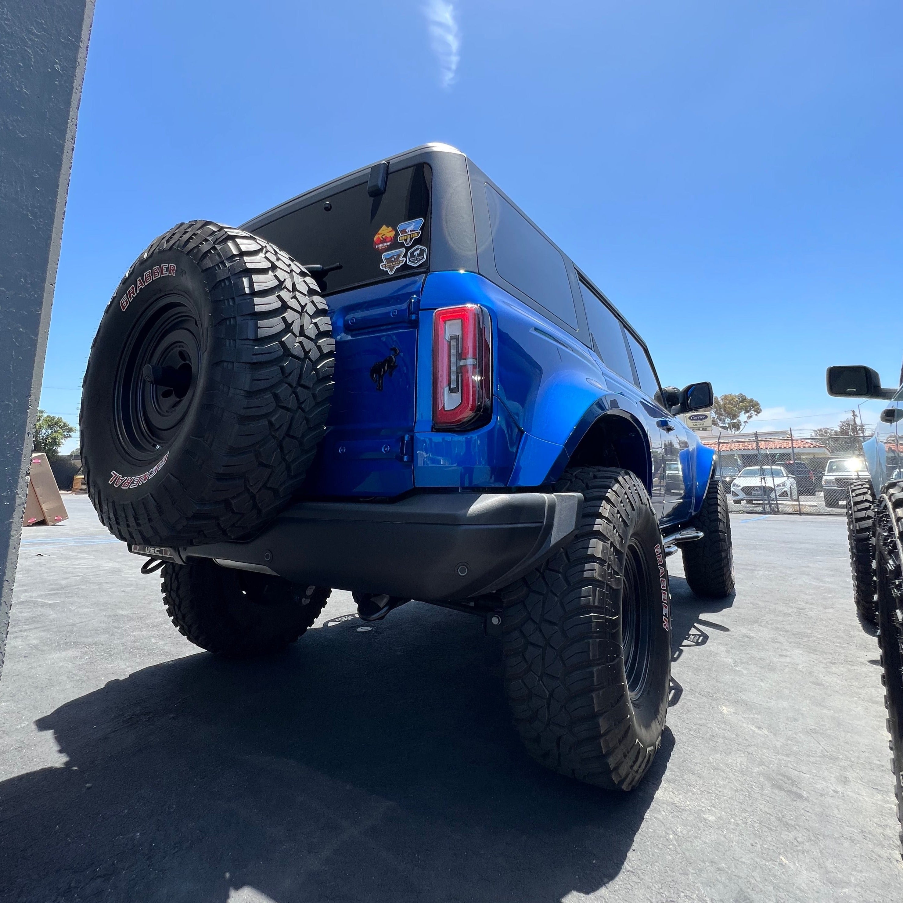 2021-2024 Ford Bronco 4-Door with rear quarter kit showcasing rugged tires and offroad design in a sunny outdoor setting.