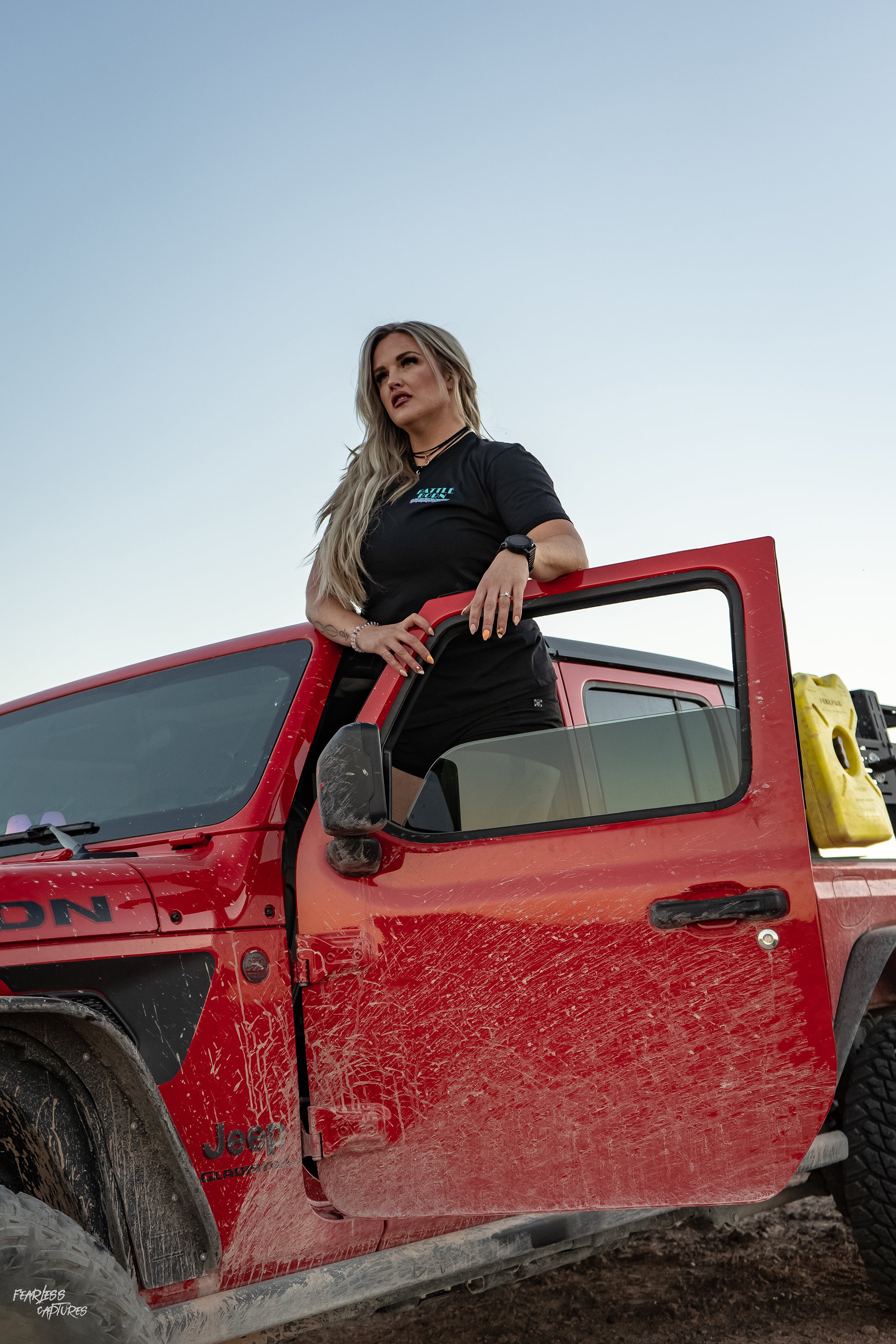 Model wearing a BBO Miami Vice T-Shirt, leaning against a red Jeep, showcasing offroad style and adventure spirit.