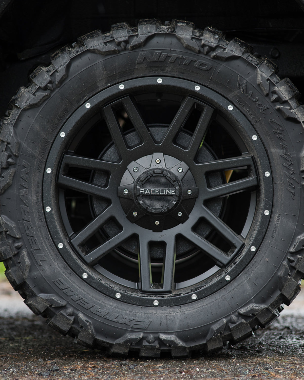 Black alloy wheel with rugged tire, showcasing a strong design ideal for offroad vehicles and enhanced performance.