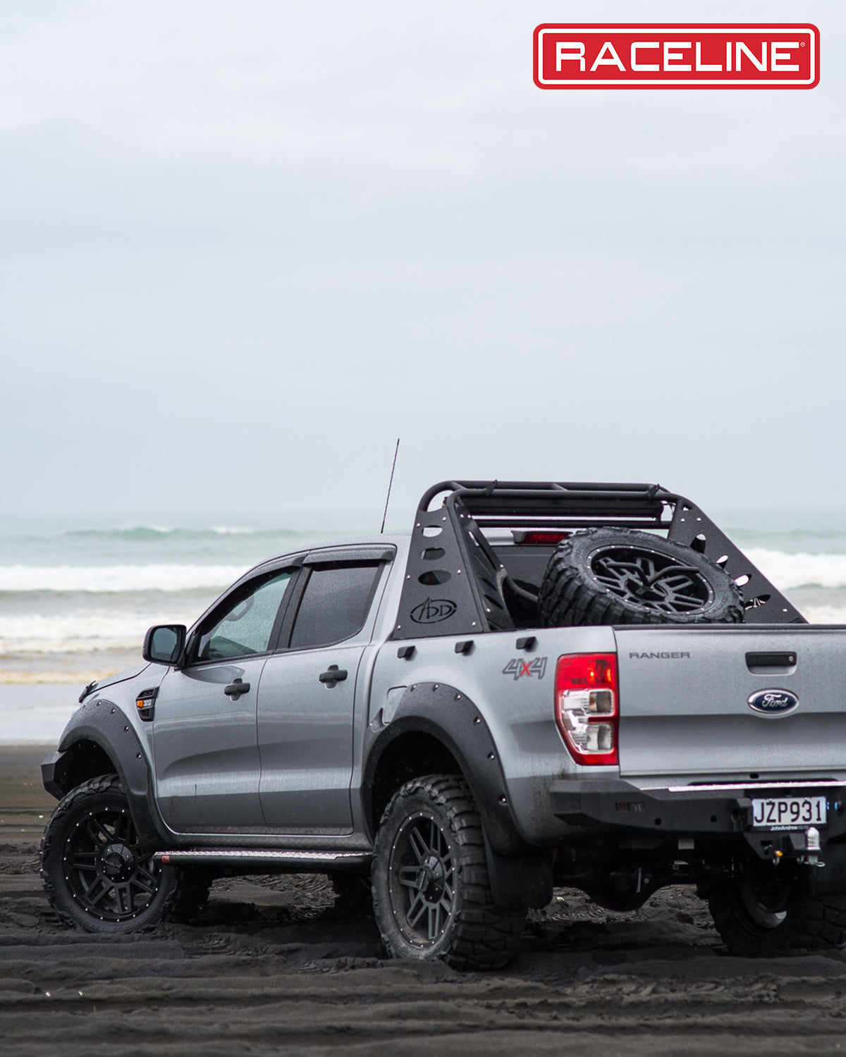 Ford Ranger equipped with Raceline wheels and offroad accessories parked on a beach, showcasing rugged design and performance.