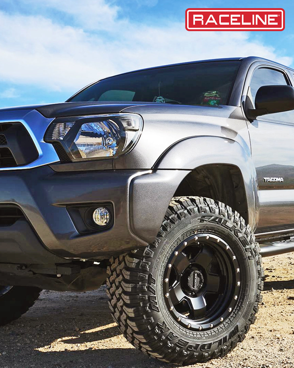 Black Raceline 937B Combat wheels on a gray Toyota Tacoma, showcasing rugged offroad tires against a desert backdrop.
