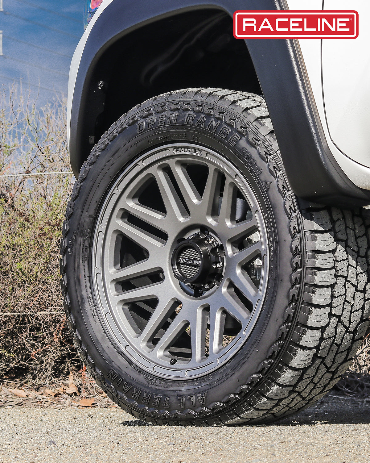 Gray 944GS Outlander wheel mounted on an offroad tire, showcasing a rugged design suitable for trucks and SUVs.