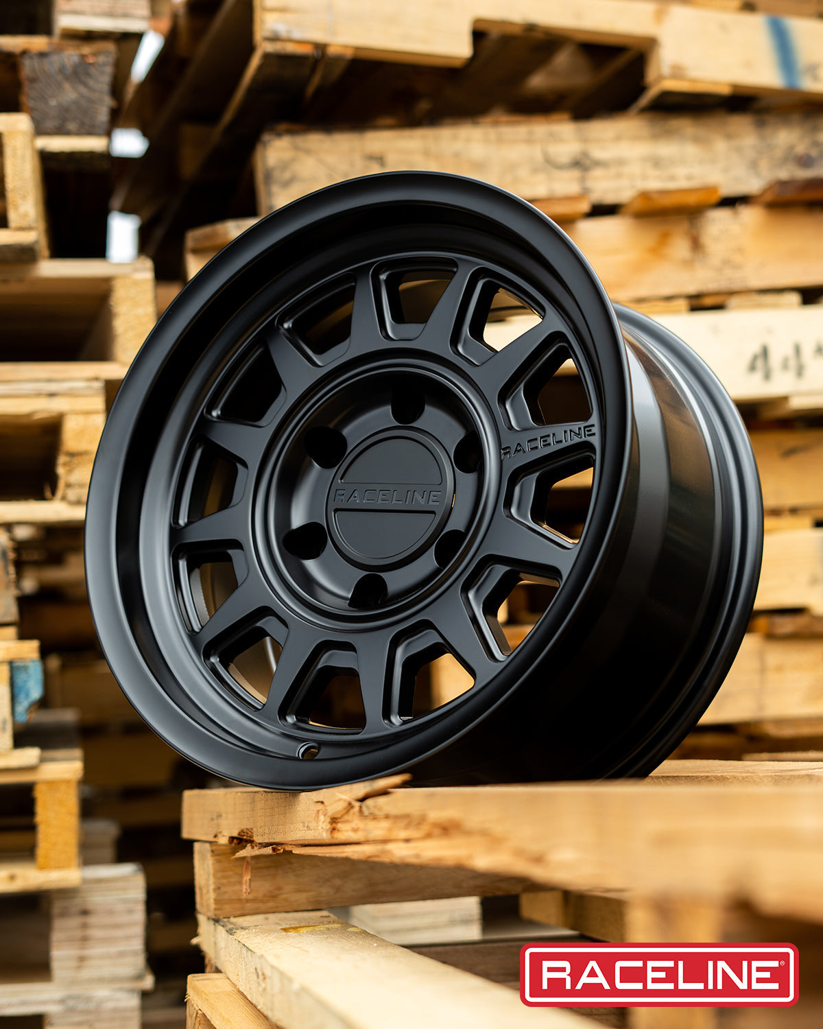 Black Raceline 952B Aero HD wheel displayed on wooden pallets, showcasing its rugged design for offroad vehicles.