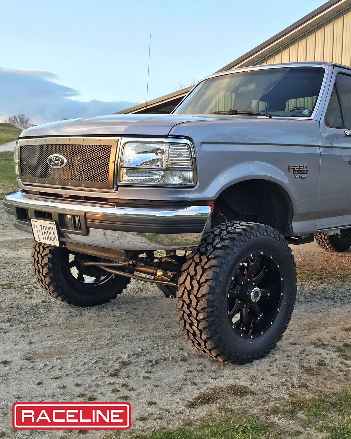 Ford truck with a lifted suspension and black wheels, showcasing the 991B Assault tires in a rugged outdoor setting.