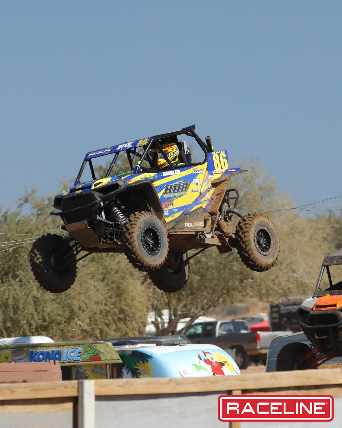 A91B Ryno Beadlock wheel on a UTV jumping over a dirt track, showcasing offroad performance and durability.