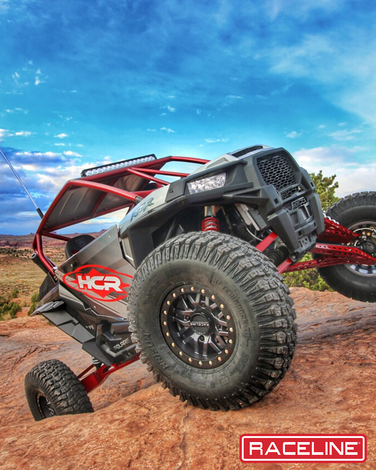 A91G Ryno Beadlock wheel mounted on an off-road vehicle climbing a rocky terrain under a blue sky.