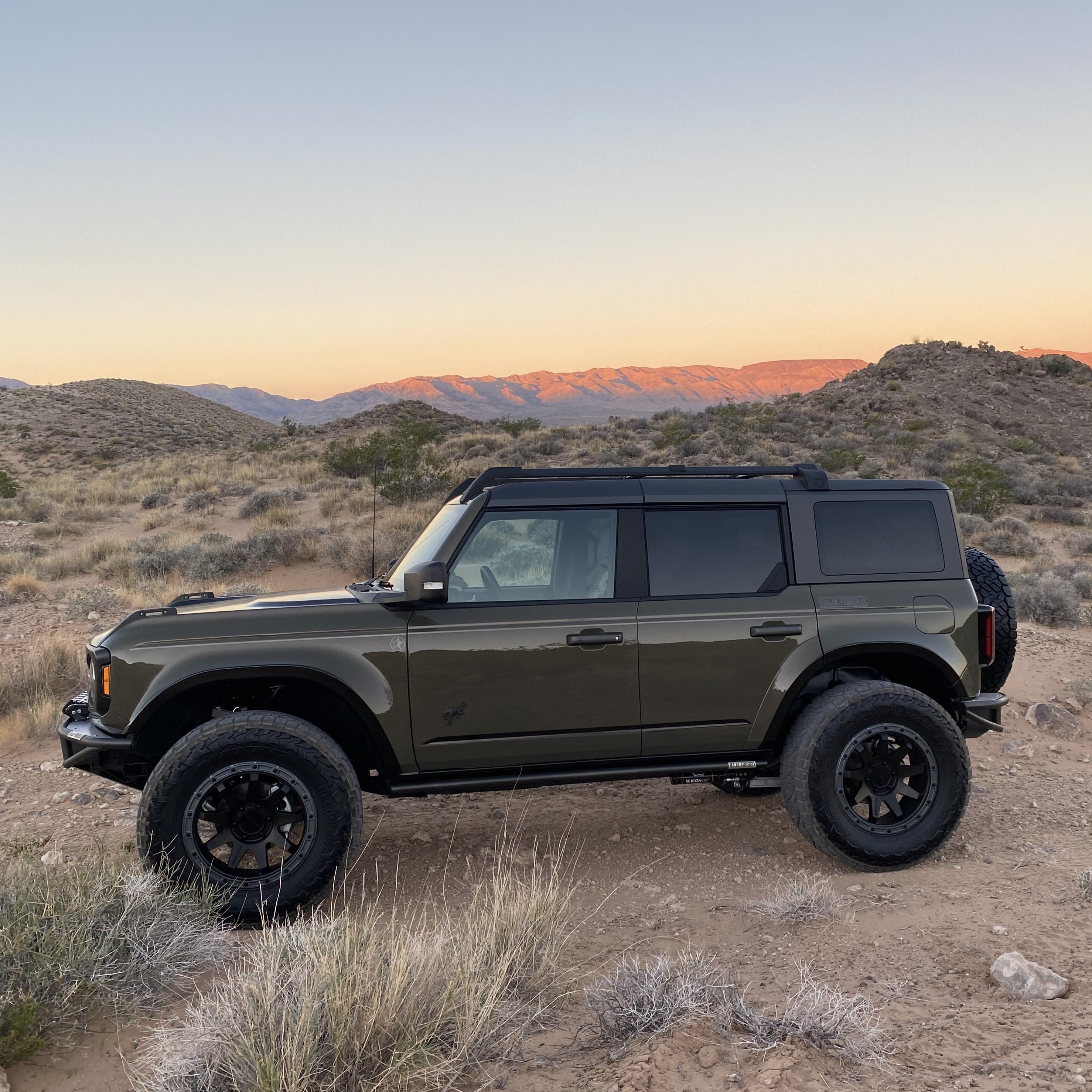 2021-2024 Ford Bronco 4-Door Rear Quarter Kit installed on a rugged Bronco in a desert landscape at sunset.